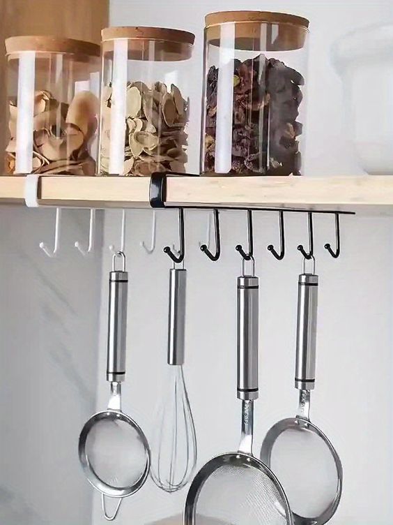 Floating shelf with hooks to hang kitchen utilities.