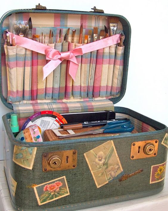 Vintage suitcase with fabric lining and compartments for storing paint supplies.