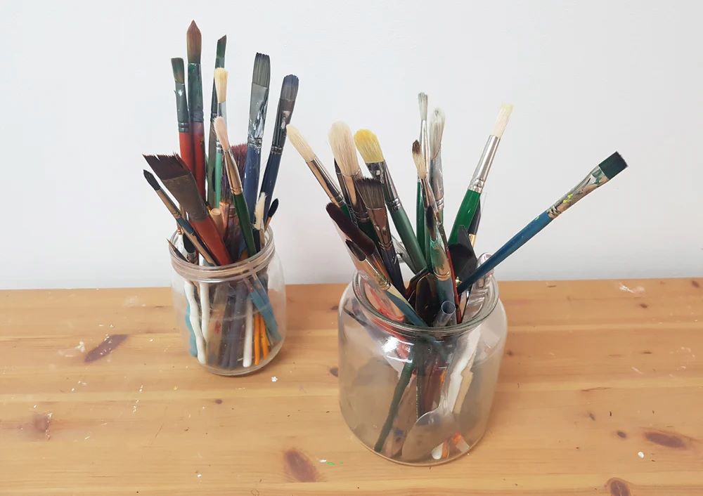 Mason jars holding paint brushes.