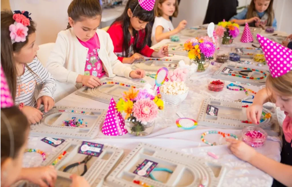 Little girls making jewellery from beads and pearls.