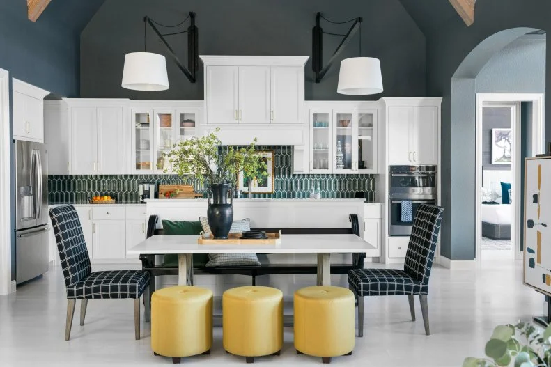 Green geometric backsplash, pops of yellow stools, and a dark moody ceiling against white cabinetry.