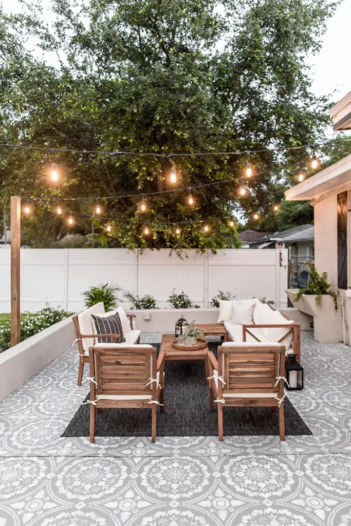 Backyard patio with modern construction and rustic furniture, enlightened with industrial fairylights.