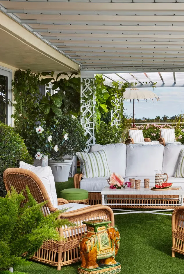 This backyard looks like a faux forest, filled with greens and cane furniture.